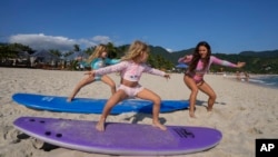 Rayana Tanimoto aprann pitit fi li yo Eloa ak Ayla kijan pou yo fe surfing sou plaj Maresias la nan Sao Sebastiao, Brezil, Samdi 27 Nov. 2021.
