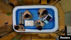 College students cool themselves inside an inflatable pool during the summer heat, at their dormitory in Wuhan, Hubei province, August 5, 2014.