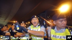 Police officers hold pepper spray cans against protesters as they try to break through a police cordon to carry out a sit-in protest in the Hong Kong's central business district, July 1, 2011.