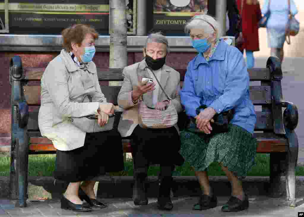 Elderly women look at a phone while sitting on a bench on Khreshchatyk Street in Kyiv, Ukraine.