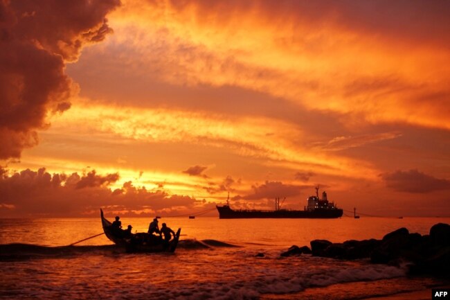 FILE - A fishing boat (L) heads out to sea at dawn in Lhokseumawe, Aceh on August 9, 2021. (Photo by Azwar Ipank / AFP)