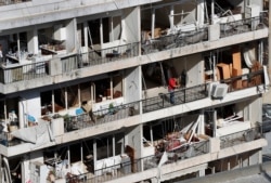 A man stands on the balcony of an apartment building damaged by Tuesday's explosion that hit the seaport of Beirut, Lebanon, Aug. 7, 2020.