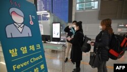 17일 한국 인천국제공항에서 육군 지원팀 소속 군인이 입국한 여행객의 체온을 측정하고 있다. 