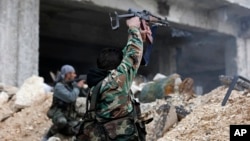 Syrian soldiers fire their weapons during a battle with rebel fighters at the Ramouseh front line, east of Aleppo, Syria, Dec. 5, 2016.