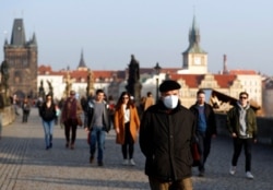 FILE - A man wearing a face mask to guard against coronavirus transmission walks across the medieval Charles Bridge in Prague, Czech Republic, Feb. 25, 2021.