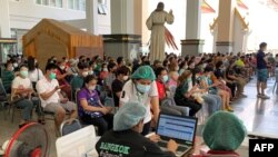 People wait to receive doses of China's Sinovac COVID-19 vaccine at the Holy Redeemer Church in Bangkok on May 30, 2021. 