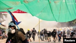 FILE - Protesters run during a crackdown on anti-coup protests at Hlaing Township in Yangon, Myanmar, March 17, 2021. 