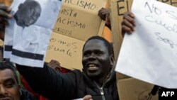 Des manifestants brandissent des pancartes et protestent après le décès d’un vendeur à la sauvette sénégalais à Lavapies, Madrid, 16 mars 2018.