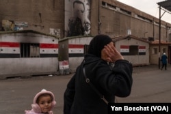 A family passes an old military office after the fall of the regime, in Damascus, Syria, on Dec. 18, 2024.