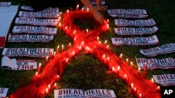 FILE - An HIV-positive Filipino lights candles around an AIDS symbol as he participates in an event in observance of World AIDS Day in Quezon city, Philippines, Dec. 1, 2016. 