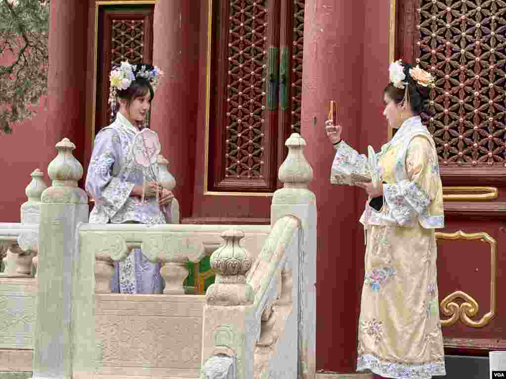 Women dressed in "Ge-ge" outfits—clothing modeled after the attire of Qing Dynasty Manchu noblewomen—takes photographs at the Forbidden City.