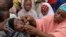 FILE - Health official administers a polio vaccine to a child in Kawo Kano, Nigeria. 
