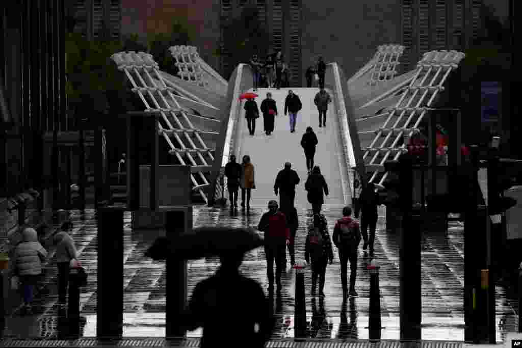 People walk across the London Millennium Footbridge.