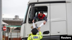 A truck driver shows the papers for a police officer at the entrance of the Port of Dover, as EU countries impose a travel ban from the UK following the coronavirus disease (COVID-19) outbreak, in Dover, Britain, Dec.22, 2020. 