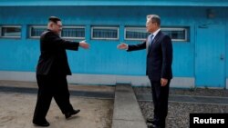 Pemimpin Korut Kim Jong Un (kiri) dan Presiden Korsel Moon Jae-in ketika bertemu di Panmunjom 27 April 2018. 