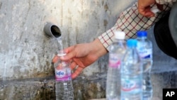 A man fills a bottle with drinkable water from a source in Sidi Bou Said, north of Tunis, on April 12, 2023. (AP Photo/Hassene Dridi)