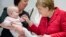 FILE - German chancellor Angela Merkel sshares a smile with the ten-month-old baby Romy at an event celebrating the 15th anniversary of the family support organization 'Wellcome ' in Berlin, March 6, 2017. 