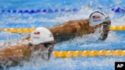 Michael Phelps (atas) beradu dengan Joseph Schooling dari Singapura dalam kompetisi gaya kupu-kupu 100-meter putra di Olimpiade Rio 2016.