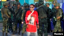 A member of the pro-government 'Red Shirt' group walks past Thai soldiers on the outskirts of Bangkok on May 22, 2014.