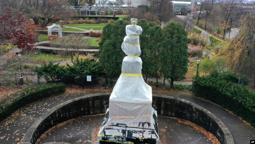 FILE - This is a statue of Christopher Columbus in the Oakland neighborhood of Pittsburgh, Pennsylvania, that was wrapped to protect it from vandalism, Nov. 26, 2020. 