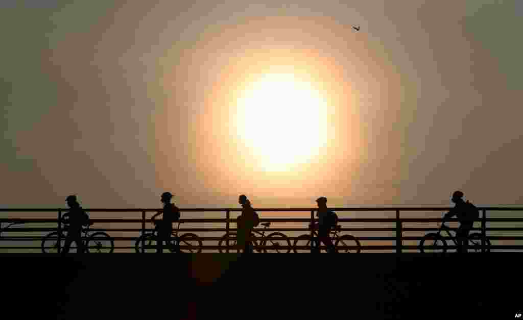 Commuters walk their bicycles across a pedestrian bridge, in Bogota, Colombia. Officials in the capital expanded bike routes, encouraging people to abandon crowded public transportation and the risk of catching the coronavirus.