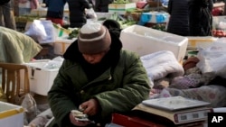 Seorang pedagang menghitung uang kertas yuan China di toko sayurnya di Beijing. (Foto: AP)