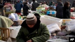 Seorang penjual menghitung uang kertas yuan China di toko sayurnya di Beijing, Kamis, 28 Januari 2016. (Foto: AP)