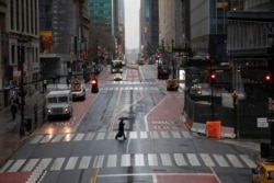 A commuter crosses 42nd Street in front of Grand Central Terminal during morning rush hour, March 23, 2020, in New York.