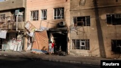 Anak-anak laki-laki tengah memeriksa lokasi terjadinya serangan bom di wilayah Tobchi, Baghdad (21/7). Sedikitnya 46 orang dilaporkan tewas dalam gelombang serangan bom mobil di beberapa kawasan kota Baghdad, Sabtu malam.