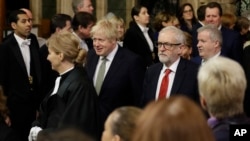 Britain's Prime Minister Boris Johnson, centre left, and opposition Labour Party Leader Jeremy Corbyn, right, walk through the Commons Members Lobby to hear the Queen's Speech in Parliament, in London, Dec. 19, 2019.