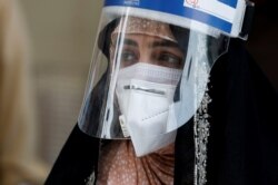 A woman wears a protective face shield and a protective face mask as she attends an event of mask distribution along a road, as the outbreak of the coronavirus disease (COVID-19) continues, in Karachi, Pakistan, June 15, 2020.