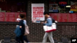 FILE - People pass a sign protesting the construction of a sports arena, in the Chinatown neighborhood of Philadelphia, Pennsylvania, Sept. 18, 2024. 