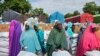 FILE- Women and villagers wait to receive food donations from the United Nations World Food Program in Damasak, northeastern Nigeria, Oct. 6, 2024.
