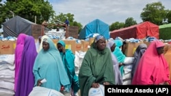 FILE- Women and villagers wait to receive food donations from the United Nations World Food Program in Damasak, northeastern Nigeria, Oct. 6, 2024.
