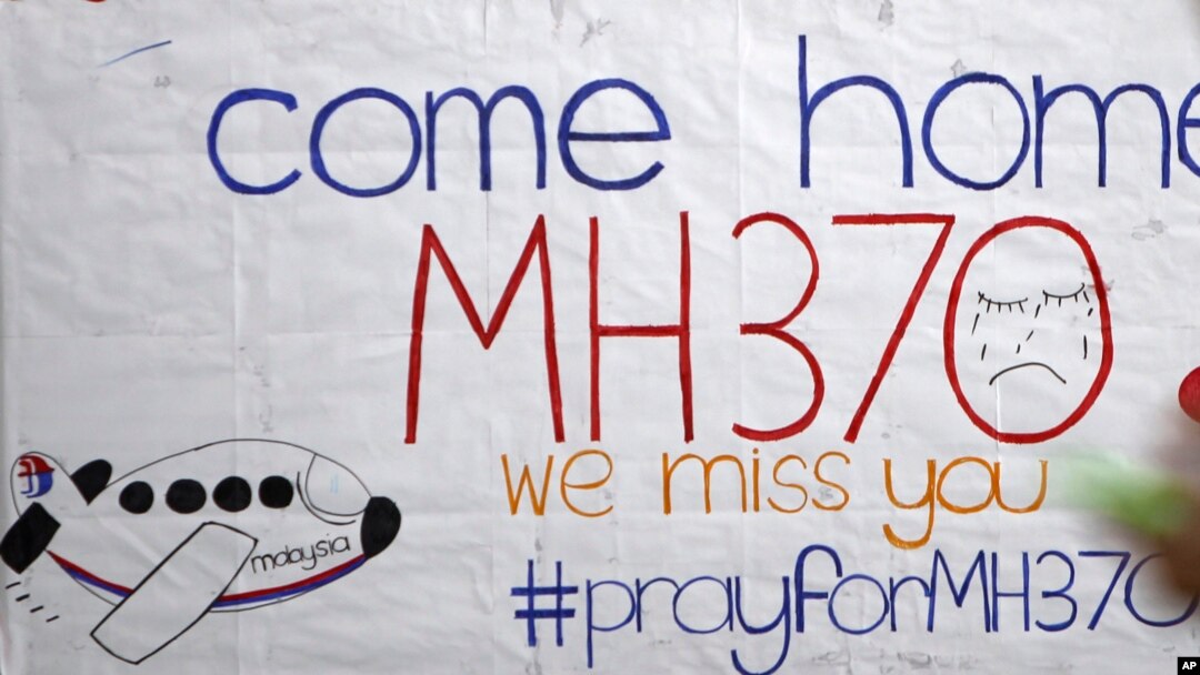 A woman stands in front of a placard featuring messages for passengers aboard a missing Malaysia Airlines plane at Kuala Lumpur International Airport in Sepang, Malaysia, March 12, 2014. 
