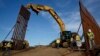 FILE - Construction crews install new border wall sections, Jan. 9, 2019, seen from Tijuana, Mexico. 