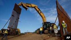 FILE - Construction crews install new border wall sections, Jan. 9, 2019, seen from Tijuana, Mexico. 