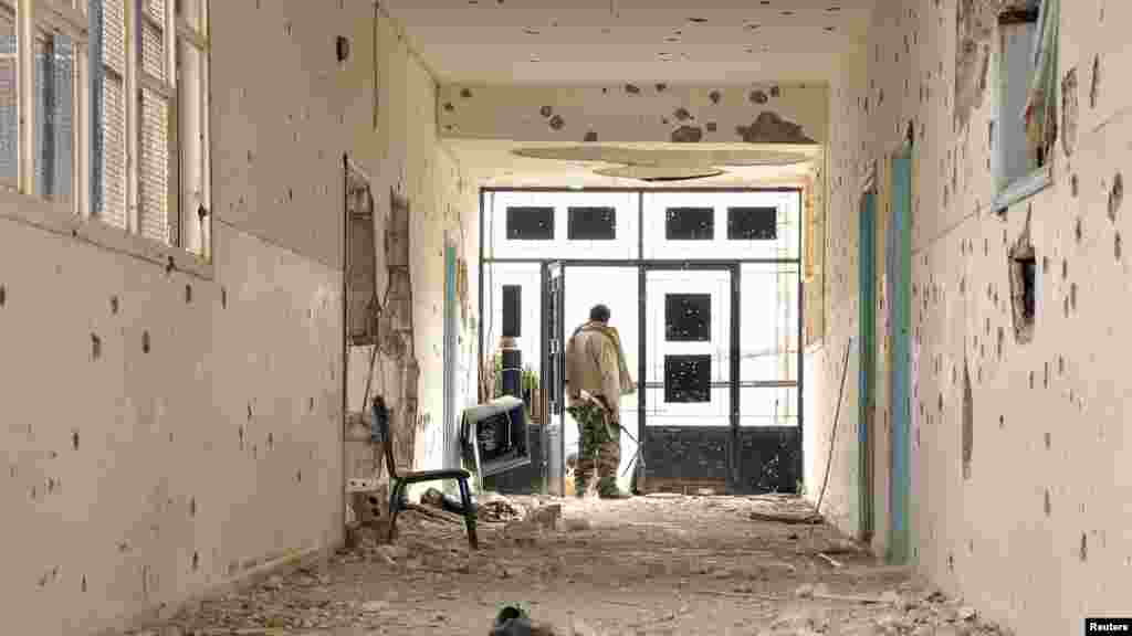 A Kurdish People's Protection Units fighter stands in a damaged school in Al-Menajir village, Ras Al-Ain countryside, Syria, Jan. 26, 2014.