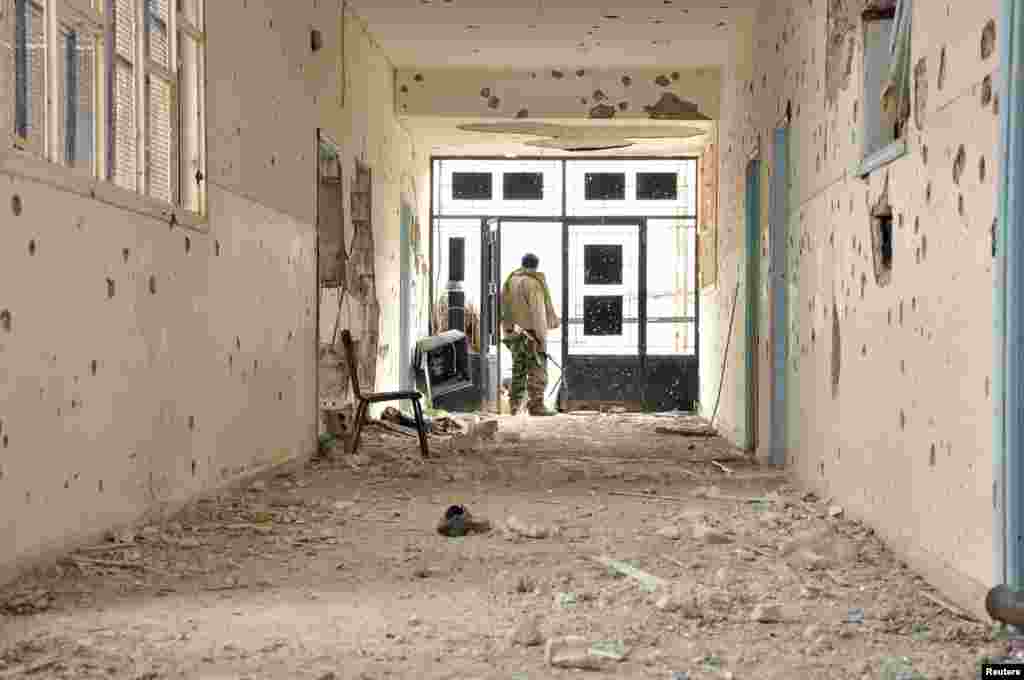 A Kurdish People's Protection Units fighter stands in a damaged school in Al-Menajir village, Ras Al-Ain countryside, Syria, Jan. 26, 2014.
