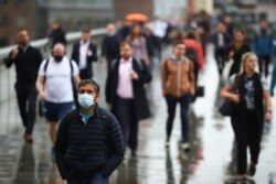 FILE - Commuters cross the London Bridge, amid the spread of the coronavirus disease (COVID-19), in London, July 6, 2021.