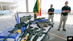 Customs and Border Protection officers stand by guns confiscated along the U.S.-Mexico border