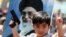 An Iraqi boy living in Iran holds a toy gun, flashes a victory sign in front of a poster of the Iranian Supreme leader Ayatollah Ali Khamenei in demonstration against Sunni militants of the al-Qaida-inspired Islamic State of Iraq and the Levant, Tehran, J