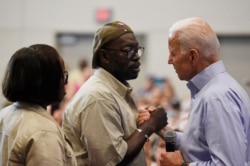 FILE - Democratic presidential candidate Joe Biden, right, greets Tyrone Sanders, husband of Mother Emanuel shooting survivor Felicia Sanders, left, during a town hall in Charleston, S.C., July 7, 2019.