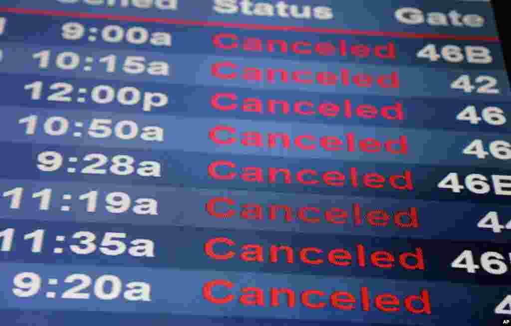 Layar-layar yang memperlihatkan jadwal penerbangan yang dibatalkan di Bandar Udara Internasional Newark Liberty di Newark, New Jersey (14/3). (AP/Seth Wenig)