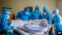 FILE - In this April 14, 2021, photo, a medical team rolls a coronavirus patient from a bed onto a stretcher in the COVID-19 intensive care unit at Kenyatta National Hospital, in Nairobi, Kenya.