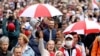 Opposition supporters carrying umbrellas in the colors of a former white-red-white fag of Belarus parade through the streets during a rally to protest against the presidential inauguration in Minsk, Sept. 27, 2020. 