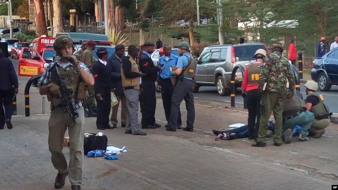 Pegawai Kedutaan Besar AS dan petugas keamanan Kenya berkumpul dekat mayat pria yang tewas ditembak di luar Kedubes AS di Nairobi (27/10). (AP/Moses Muoki)