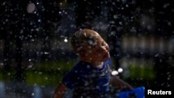 Seorang anak bermain air untuk mendinginkan dari cuaca panas ekstrem di Washington DC, 20 Juli 2019. (Foto: Reuters)