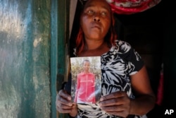 FILE - Rose Wanyua Wanjiku, elder sister to Agnes Wanjiru, 20, who was allegedly killed by a British soldier in 2012, holds a photograph of Agnes, at Rose's house in the Majengo informal settlement in Nanyuki, Kenya, , November. 4, 2021.