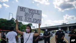 A protester holds a sign in front of police, near the Wendy's restaurant in Atlanta where Rayshard Brooks was fatally shot by police the night before, June 13, 2020.